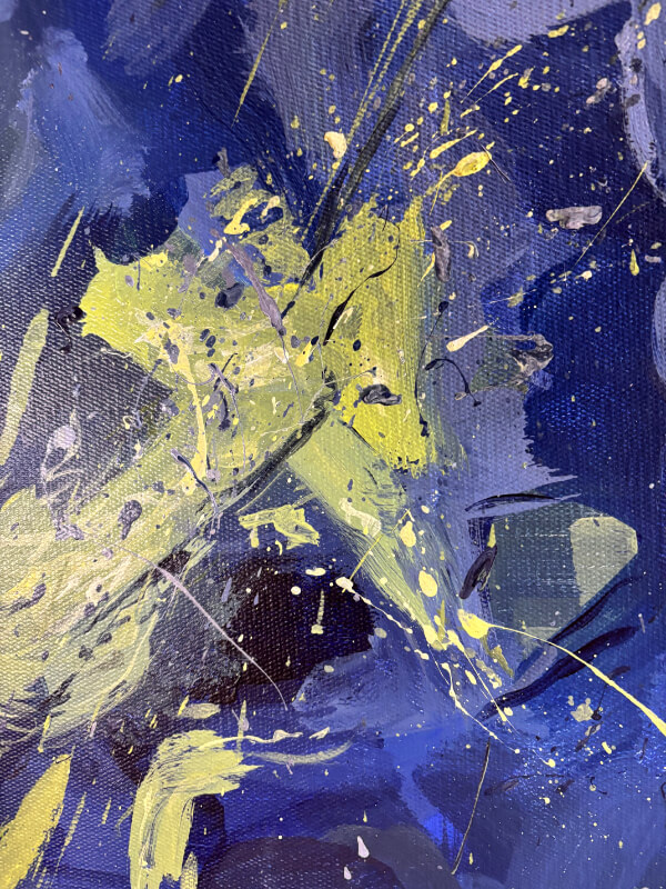 Close-up of an abstract acrylic painting with a bold yellow-green splash over rich blue tones, marked by energetic drips and scattered splatters.